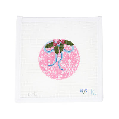 Hand-painted needlepoint canvas of a pink Christmas ornament with white snowflake pattern, topped with holly and a blue bow—perfect for holiday stitching and festive finishing