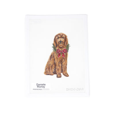 Hand-painted 18 mesh needlepoint canvas featuring a highly detailed brown Goldendoodle wearing a festive Christmas bow and holly around its neck. Designed as a beautiful ornament, perfect for holiday decorating, gifting, or commemorating a beloved pet