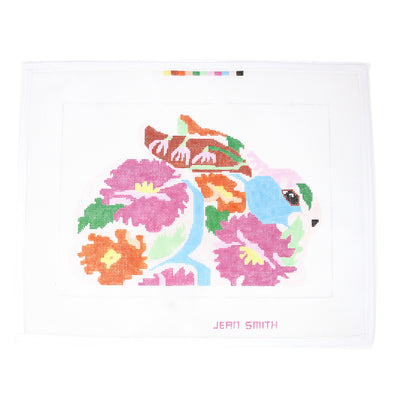 Bashful Bunny needlepoint canvas by Jean Smith, featuring a bunny covered in vibrant floral designs in pink, yellow, and blue. Printed on 18-count mesh, perfect for framed art, pillows, or ornaments. Add beads or embroidery for extra detail. Mesh size: 18-count