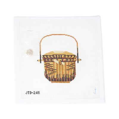 Hand-painted needlepoint canvas of a Nantucket basket with a seashell charm on 18 mesh, perfect for coastal, nautical, or summer-themed stitching projects.