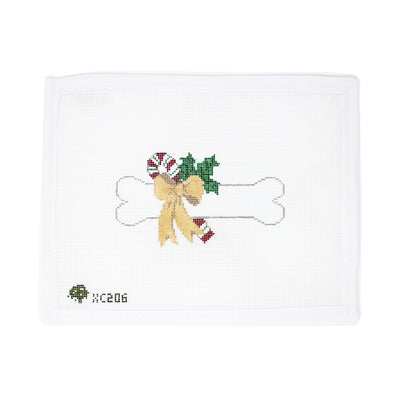 Festive needlepoint canvas featuring a dog bone adorned with a red Christmas bow, holly leaves, and a candy cane, hand-painted on 18 mesh. Perfect for finishing as a holiday ornament, gift tag for a pet lover, or a charming addition to a Christmas garland.