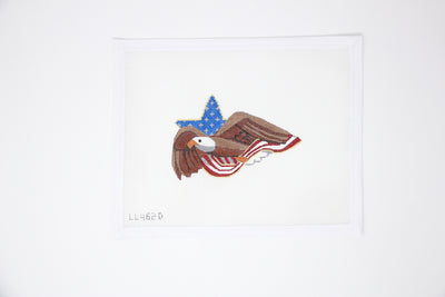 Needlepoint canvas of a flying bald eagle in front of a background featuring a star and American flag design. Hand-painted in a patriotic red, white, and blue color scheme.